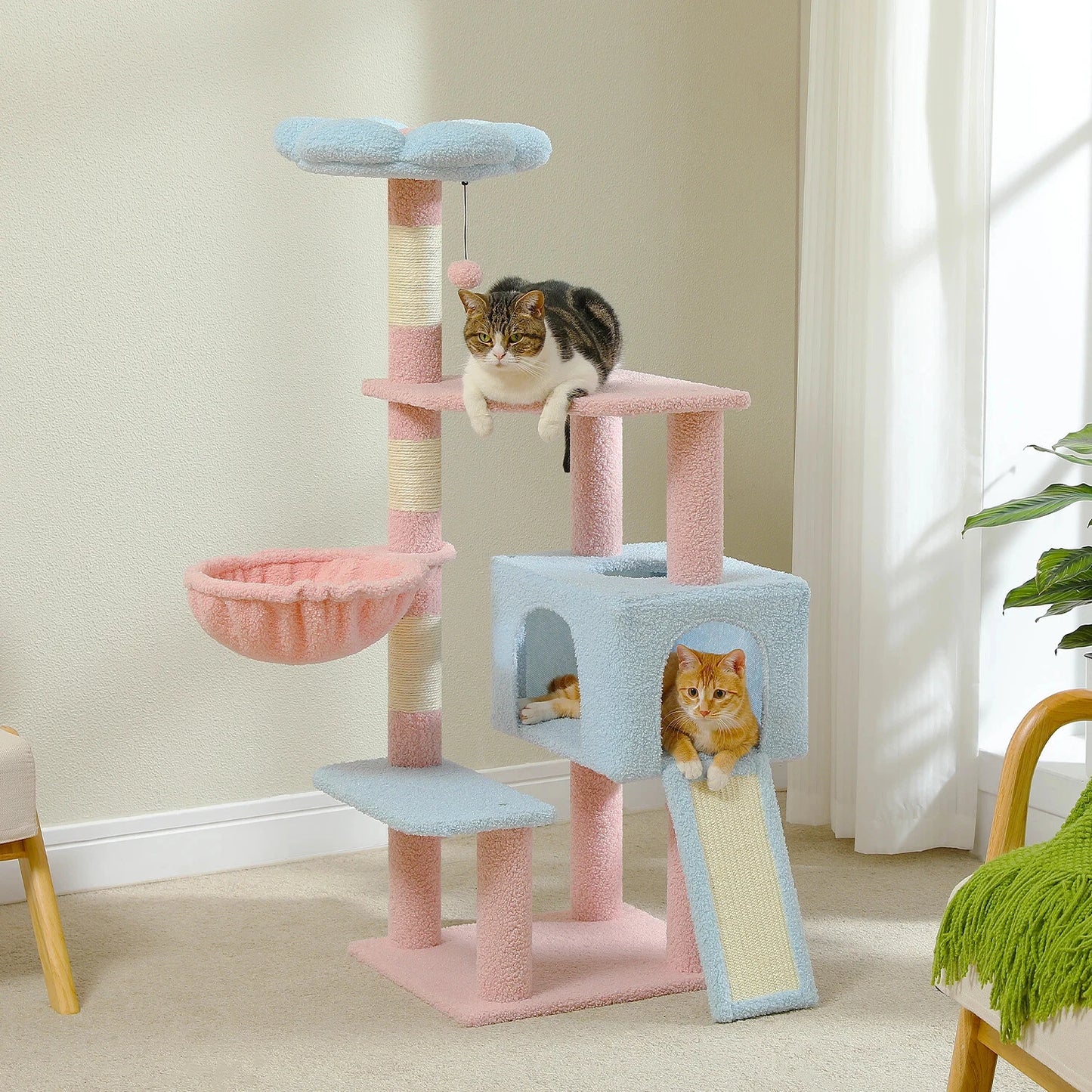 Cat tree with multiple levels and a cat sitting on top in a room with light-colored walls and a plant.